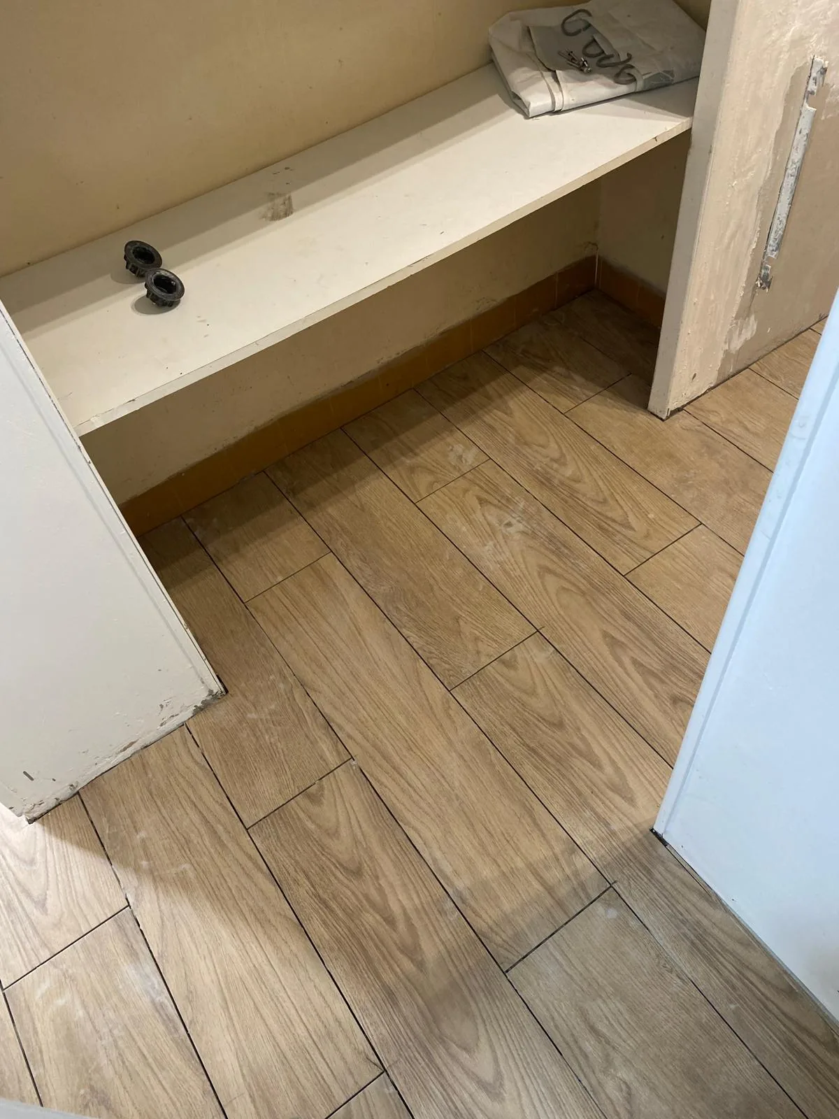 Petite piece avec tablette maconnee blanche, mur creme a bandeau ocre en soubassement, sol en carrelage effet bois chene pose en decale
