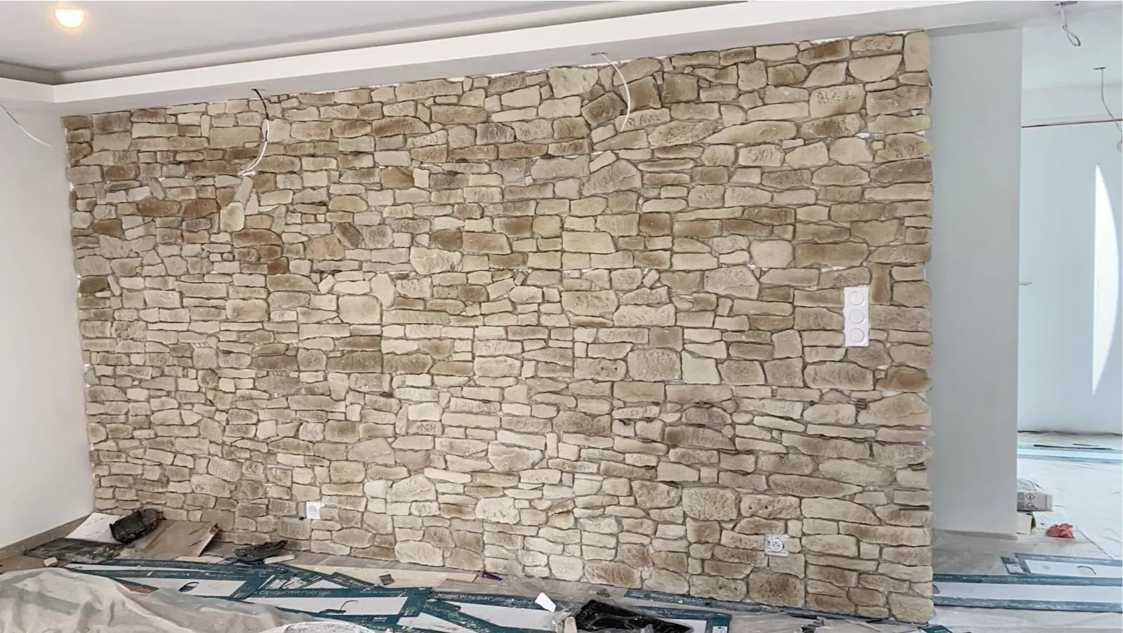 Grand mur interieur habille de plaquettes de pierre de parement beige a joints irreguliers