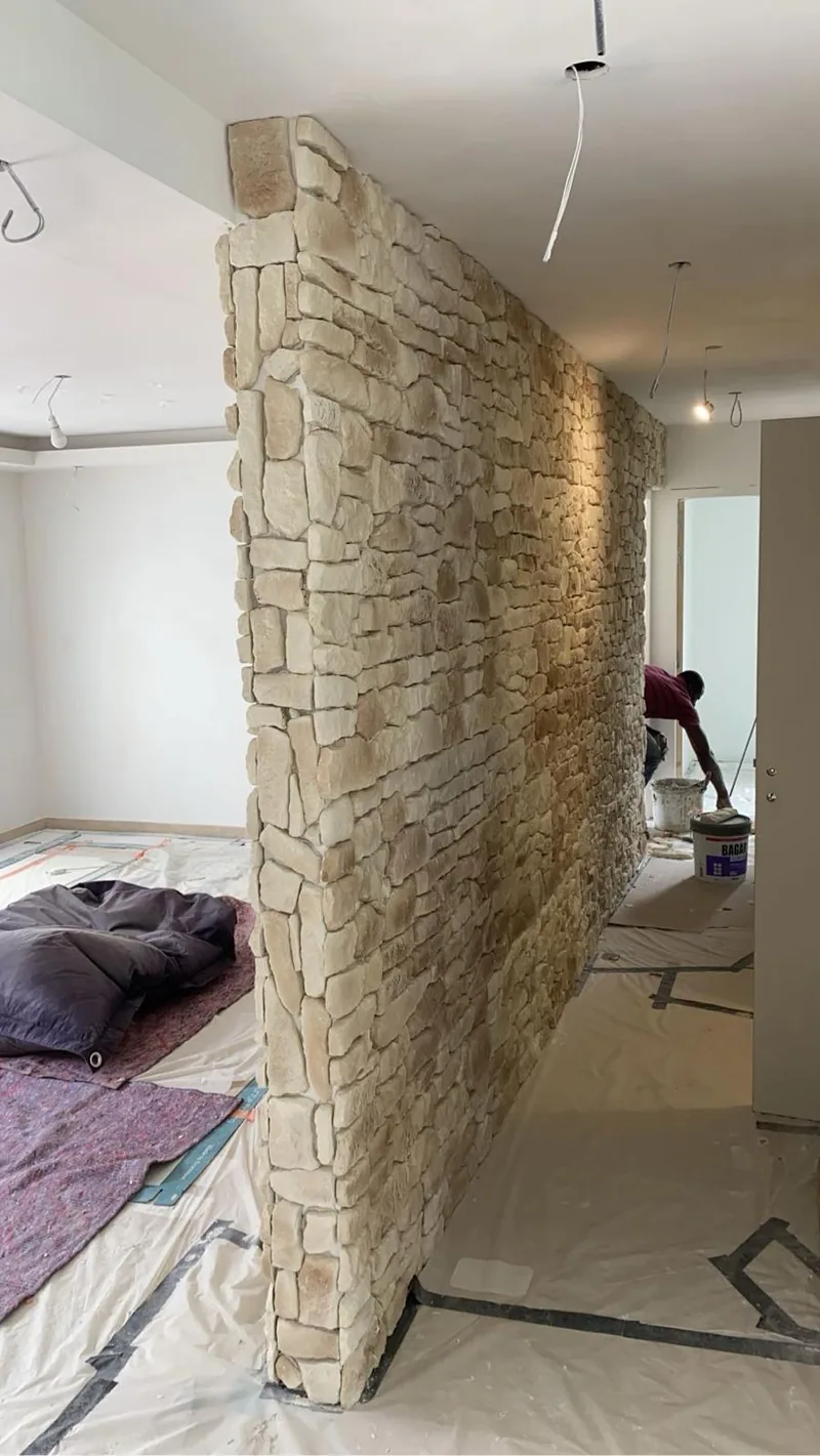 Cloison interieure habillee de pierre de parement beige vue de biais, montrant l arete d angle habillee en pierre