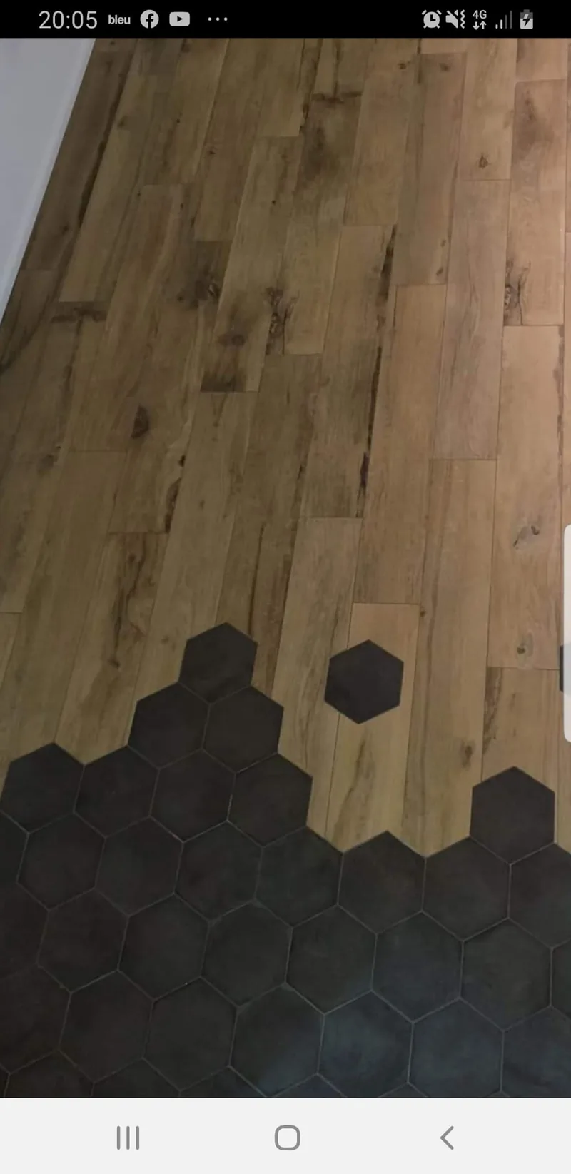 Sol associant un carrelage imitation bois et des carreaux hexagonaux noirs, la jonction dessinant un dégradé d'hexagones qui avancent dans les lames