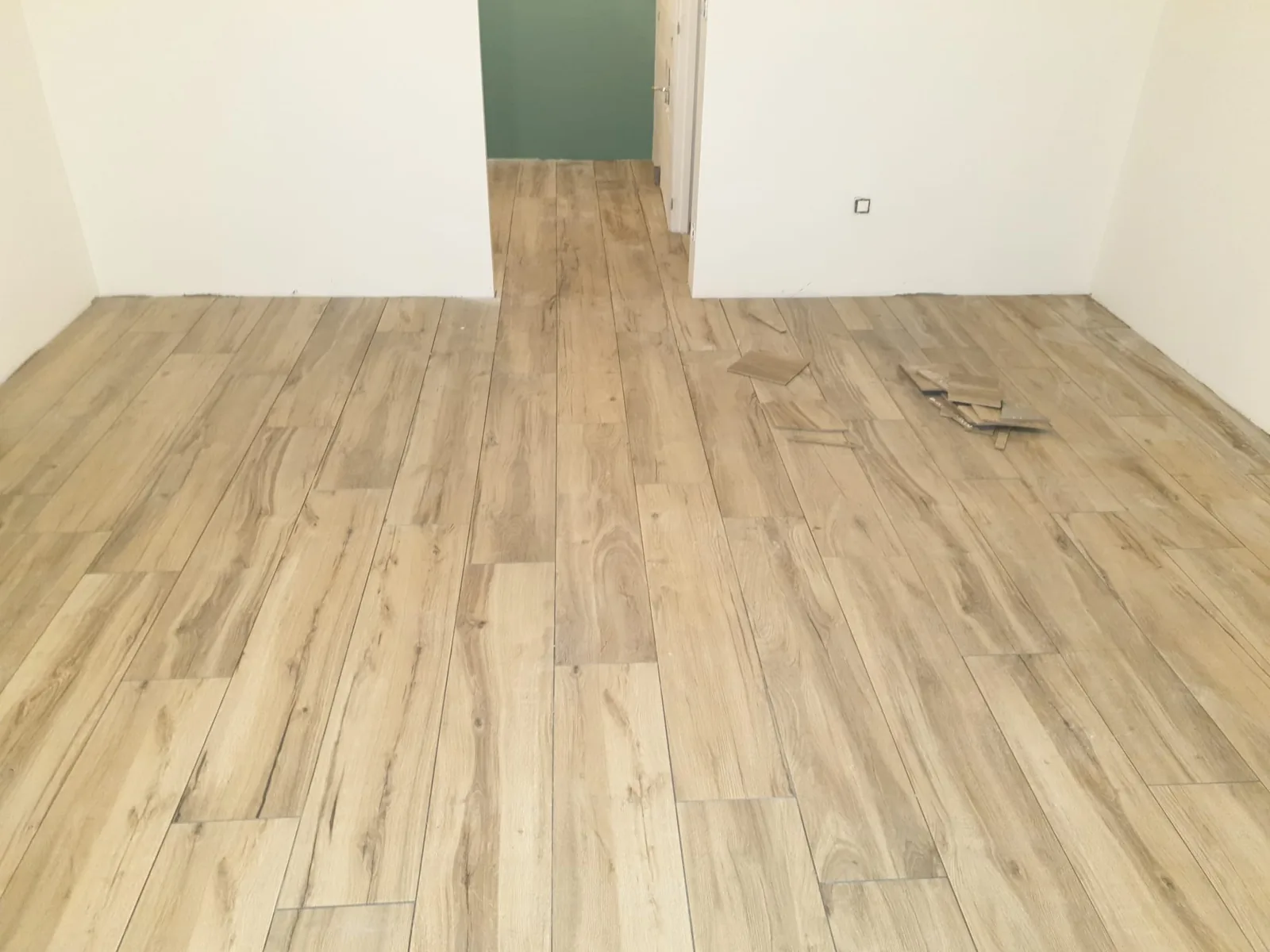 Pièce vide avec sol en carrelage imitation bois clair et un mur peint en vert